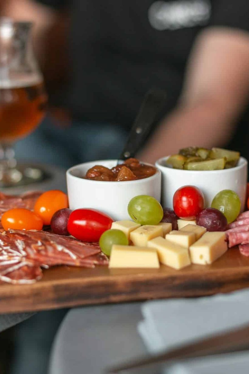 A delicious spread of cheese and charcuterie, chutney and pickles, grape and tomatoes