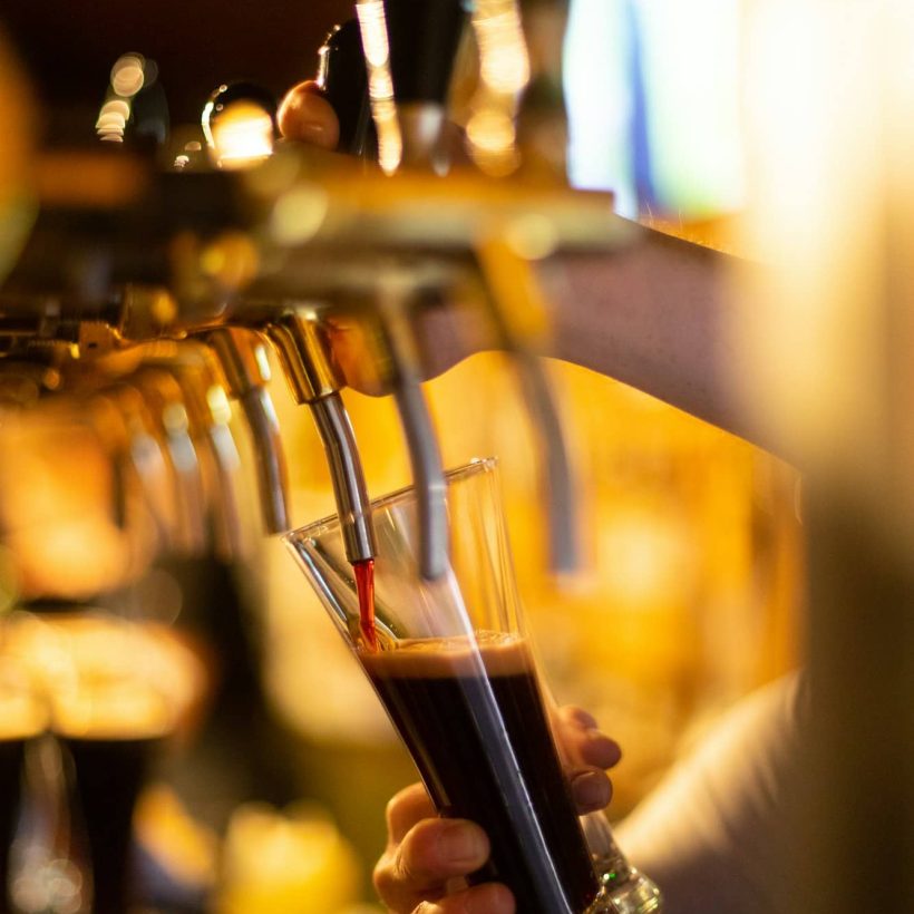 Dark beer is poured into a glass of beer tap